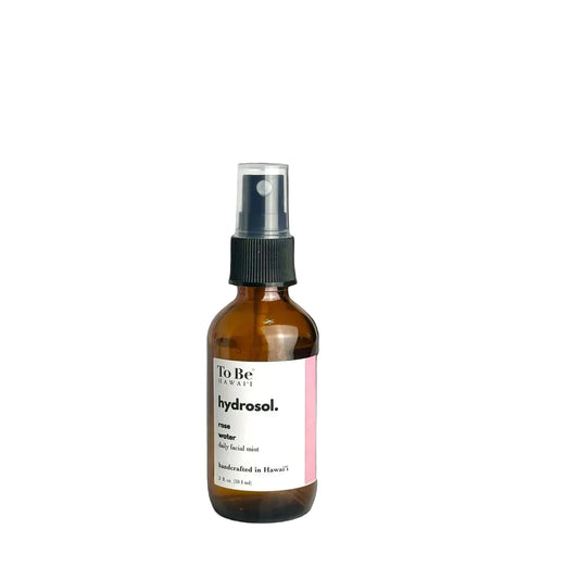 A brown bottle with a spray nozzle containing rose hydrosol, labeled 'To Be Hydrosol. 100% Rose water. Distilled in Hawaii'.