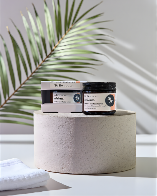 To Be Bamboo and Acai Facial Scrub products on a white surface with a plant in the background