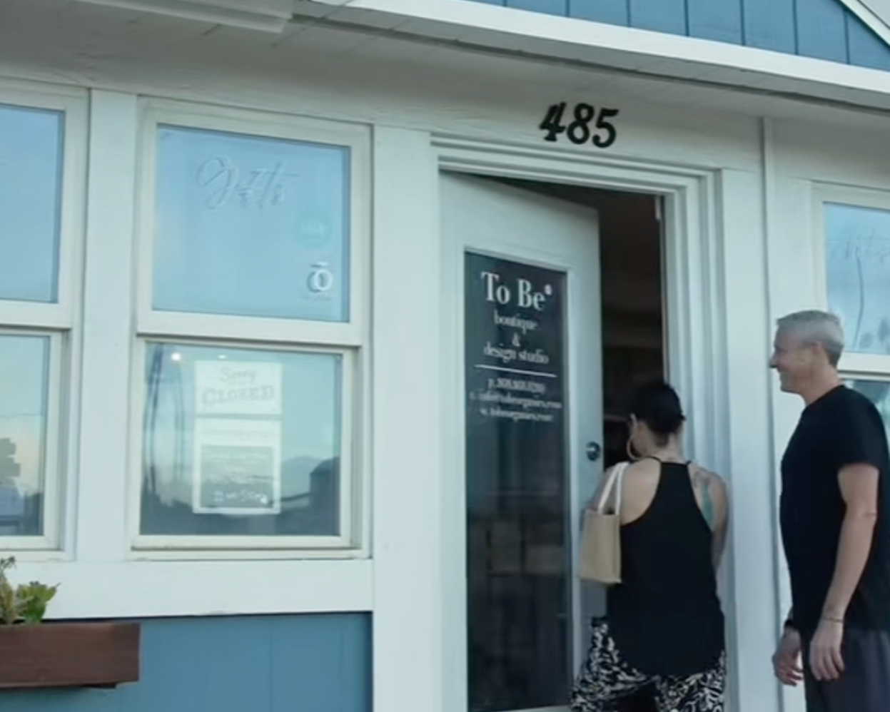 Owners Karli Rose & Michael  standing outside their store named 'To Be' with a sign above the door.