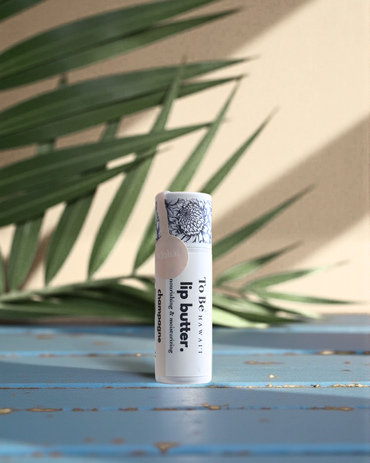 Champagne Lip butter on a blue surface with green leaves in the background