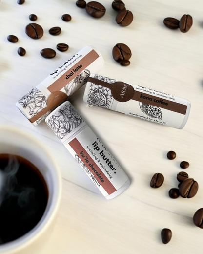Lip butter with coffee-themed packaging on a surface with coffee beans and a cup of coffee.