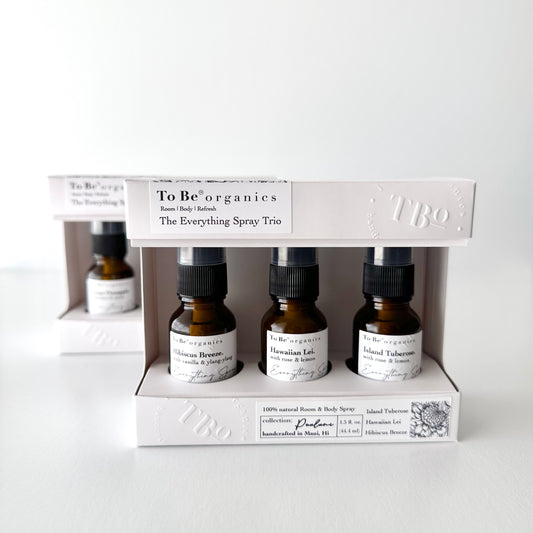 Three small amber glass misters with white labels in eco-friendly cardboard packaging, labeled as 'The Everything Spray Trio' by To Be Hawaii'