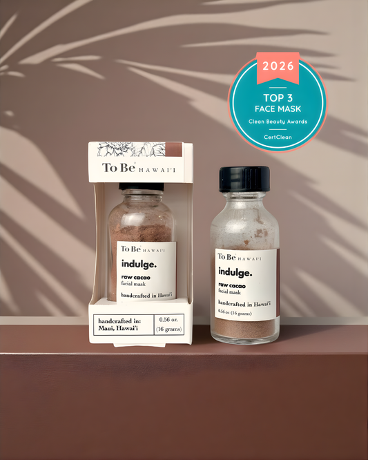 Two bottles of 'indulge' face mask by To Be Hawaii on a brown background with palm leaf shadows. A clean beauty award badge is displayed for 2026 top 3 masks.