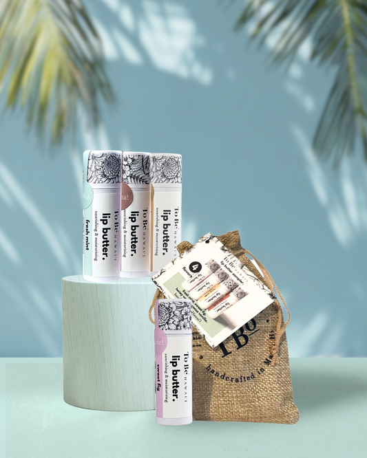 Four lip butters, Fresh mint, Kuia chocolate, Honey vanilla and sweet fig with a burlap drawstring bag on a green surface.