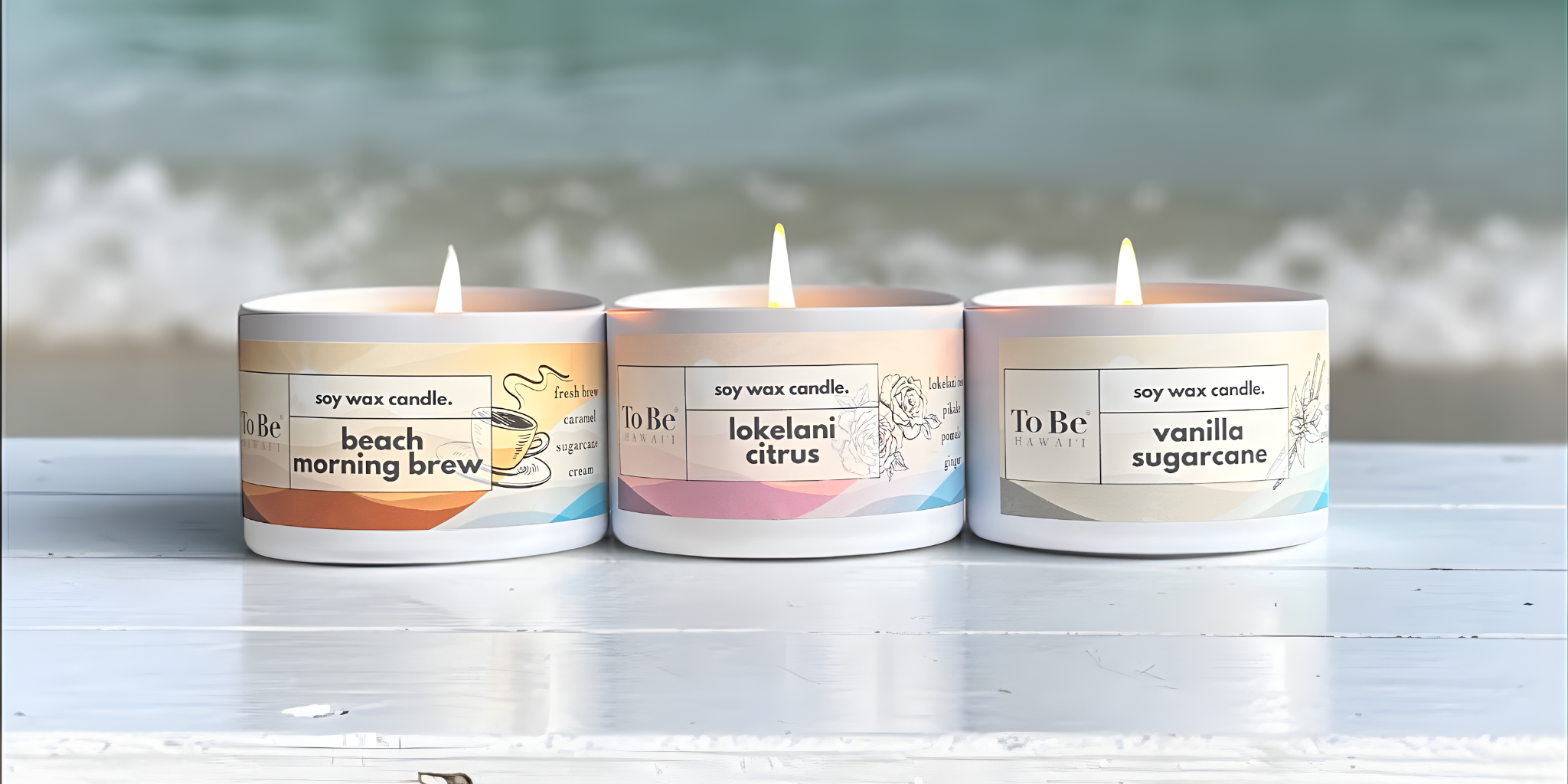 Three lit candles with labels on a white surface with a blurred natural background. 
