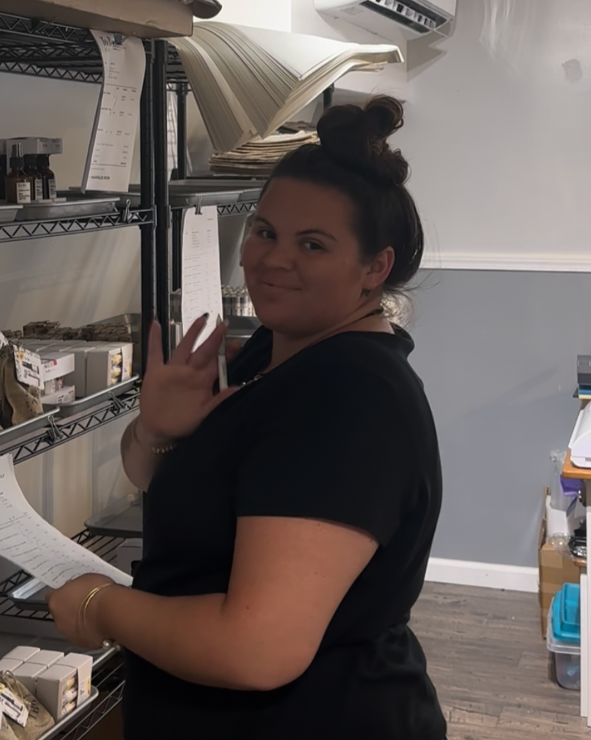 Person standing in a kitchen or storage area with shelves and appliances.