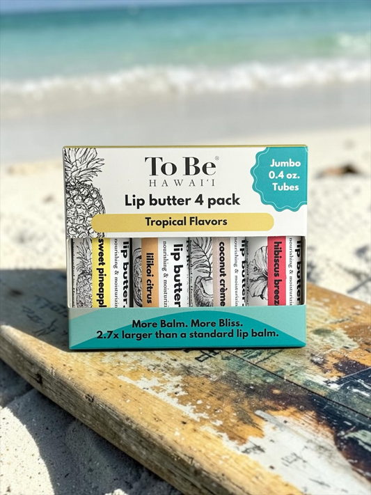 To Be Hawaii Lip Butter 4 pack in Tropical Flavors, displayed on a weathered wooden board on a sandy beach with the ocean in the background.